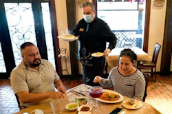 In this Wednesday, March 10, 2021 file photo, waiter Jose Bravo, center, delivers food for Alberto Castaneda, left, and his wife, Esther, at Picos restaurant in Houston. The Institute for Supply Management, an association of purchasing managers, reported Monday, April 5 that the U.S. services sector, which employs most Americans, recorded record growth in March as orders, hiring and prices all surged.