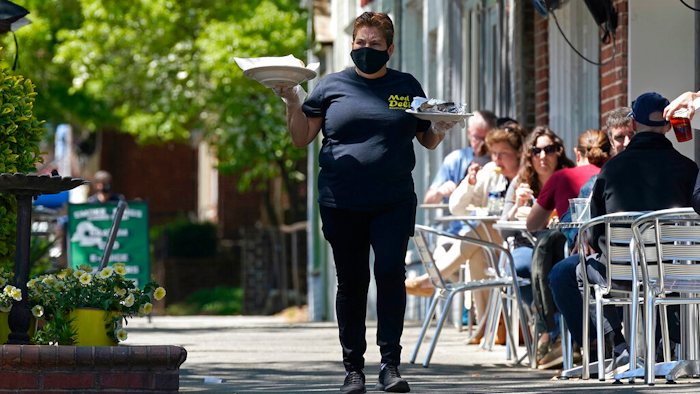 A member of the wait staff delivers food to outdoor diners along the sidewalk at the Mediterranean Deli restaurant in Chapel Hill, NC on April 16.