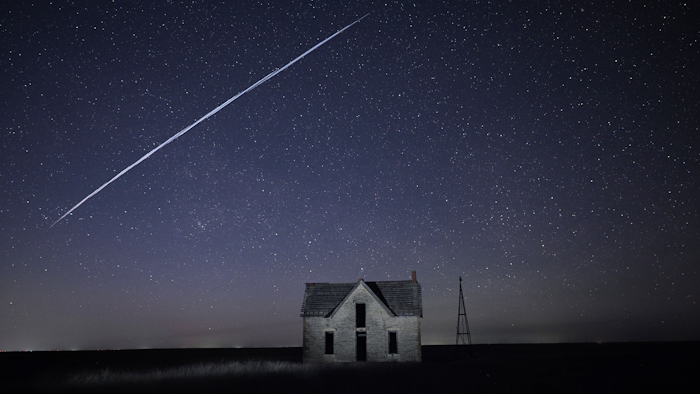 Long-exposure photo of a string of SpaceX Starlink satellites over an old stone house near Florence, Kan., May 6, 2021.