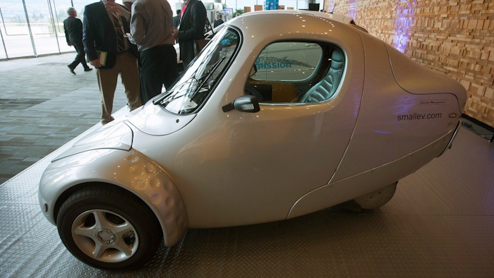 Delegates talk near an ElectraMeccanica single-user electric vehicle during the inaugural B.C. Tech Summit in Vancouver, B.C., on Monday, Jan. 18, 2016.