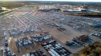 In this aerial photo, a General Motors assembly plant is seen at top right while mid-sized pickup trucks and full-size vans currently produced at the plant are seen in a parking lot outside on March 24 in Wentzville, Mo.