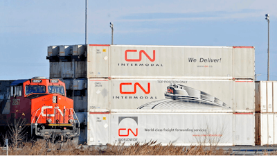 In this May 13 photo, a Canadian National locomotive passes by freight containers at the Canadian National Taschereau yard in Montreal.