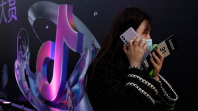 A woman speaks on her phone near the logo for Douyin in Beijing. China's internet watchdog said it had found Bytedance's Douyin, Microsoft Bing, LinkedIn and 102 other apps were engaged in improper collection and use of data and ordered them to fix the problem.