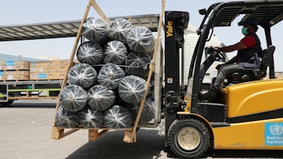 A forklift driver loads material for temporary shelters to be sent to India.