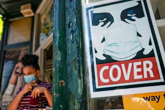 A customer exits a corner market while wearing a protective mask in the retail shopping district of the SoHo neighborhood of the Manhattan borough of New York, Friday, May 14, 2021. Gov. Andrew Cuomo has yet to say whether he will change his state’s mask mandate in light of new federal guidance that eases rules for fully vaccinated people.