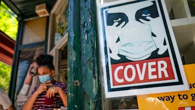 A customer exits a corner market while wearing a protective mask in the retail shopping district of the SoHo neighborhood of the Manhattan borough of New York, Friday, May 14, 2021. Gov. Andrew Cuomo has yet to say whether he will change his state’s mask mandate in light of new federal guidance that eases rules for fully vaccinated people.