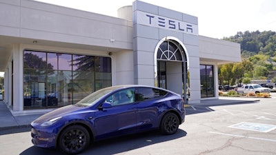 In this April 2, 2021 file photo two women in an electric car drive into a Tesla delivery location and service center in Corte Madera, Calif. California’s Department of Motor Vehicles is reviewing whether Tesla is violating a state regulation by advertising its vehicles as being fully autonomous without meeting the legal definition of self-driving The department says Monday, May 17, 2021 that the regulation prohibits advertising vehicles for sale or lease as autonomous if the regulation isn’t met.