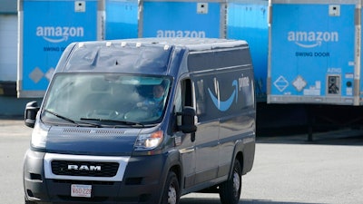 In this Oct. 1, 2020, file photo, an Amazon delivery van departs an Amazon Warehouse in Dedham, Mass. The Teamsters, a union that represents 1.4 million delivery workers, is setting its sights on Amazon. The union is voting Thursday, June 24, 2021, on whether to make organizing Amazon workers its main priority, saying that Amazon, which is now the nation’s second-largest private employer, is exploiting its employees by paying them low wages, pushing them to work at fast speeds and offering no job security.