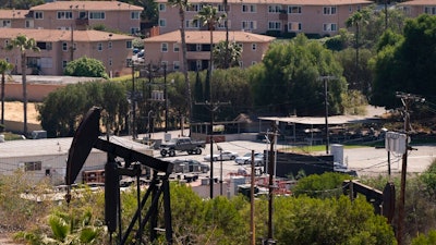 In this May 18, 2021, file photo, apartment buildings rise behind pump jacks operating at the Inglewood Oil Field in Los Angeles. California state oil regulators missed a spring deadline for new regulations designed to protect health and safety near oil and gas drillings sites. Environmental advocates have been pressuring Gov. Gavin Newsom's administration to adopt mandatory distances between wells and sites like schools and homes.