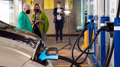 In this Thursday, April 22, 2021 file photo, White House climate adviser Gina McCarthy, left, talks with EVgo Chief Executive Officer Cathy Zoi, before the start of an event near an EVgo electric car charging station at Union Station in Washington. If the auto industry is to succeed in its bet that electric vehicles will soon dominate the roads, it will need to overcome a big reason why many people are still avoiding them: Fear of running out of juice between Point A and Point B.