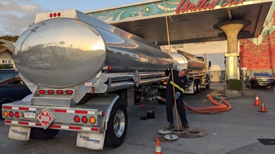 In this photo, a fuel truck driver checks the gasoline tank level at a United Oil gas station on Sunset Blvd., in Los Angeles.