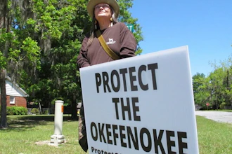 Jane Winkler stands with a sign outside a church where Georgia Gov. Brian Kemp met with local Chamber of Commerce members, Folkston, Ga., April 22, 2021.