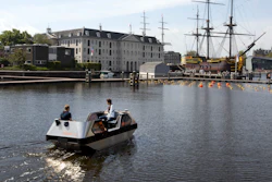 An electric boat steers close to a full-size replica of the 18th century three-mast trading ship Amsterdam at the National Maritime Museum, in Amsterdam, Thursday, May 20, 2021. Already steeped in maritime history, the city's more than 100 kilometers (60 miles) of waterways are to start hosting prototypes of futuristic boats — small, fully-autonomous electric vessels — to carry out tasks including transporting passengers and picking up garbage.