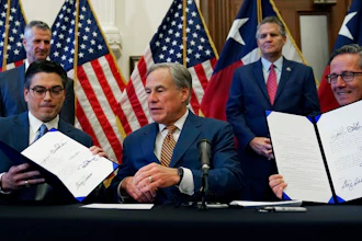 With the help of state Rep. Chris Paddie, left, and state Sen. Kelly Hancock, right, Texas Gov. Greg Abbott, center, displays two energy related bills he signed, Tuesday, June 8, 2021, in Austin, Texas. Abbot signed legislation into law to reform the Electric Reliability Council of Texas (ERCOT) and weatherize and improve the reliability of the state's power grid.