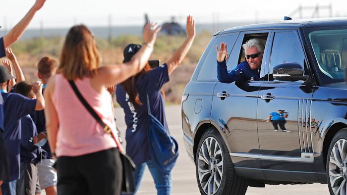 Virgin Galactic founder Richard Branson waves to school children while heading to board the rocket plane that will fly him to space from Spaceport America near Truth or Consequences, New Mexico, Sunday, July 11, 2021.