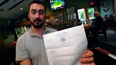 David Culhane, owner of the White Mountain Tavern, holds up a November 2020 letter from the New Hampshire attorney general's office, July 13, 2021, Lincoln, N.H.