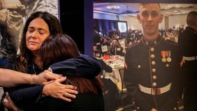 Aleta Bath, mother of Private First Class Evan Bath, and Lupita Garcia, mother of Marine Lance Corporal Marco Barranco, embrace at a press conference next to a picture of Marine Lance Corporal Chase Sweetwood, July 29, 2021, Oceanside, Calif.