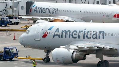American Airlines passenger jets prepare for departure, Wednesday, July 21, 2021, near a terminal at Boston Logan International Airport, in Boston. American Airlines is planning to invest in a small South American budget airline as part of a deal that will include selling seats on each other's flights. American announced the proposed deal with JetSmart on Thursday, July 29.