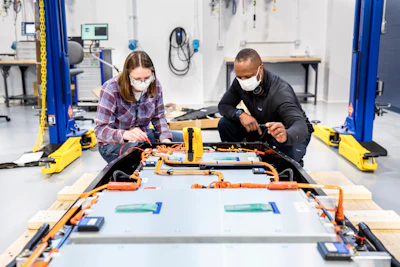 Dane Hardware, Ford Motor Co. design and release engineer, and Mary Fredrick, Ford Motor Co. battery validation engineer, measure the voltage of a battery using a digital multi-meter at Ford’s Battery Benchmarking and Test Laboratory in Allen Park, Michigan. Since this battery is not connected to a test setup, the meter is used to confirm the battery voltage and check isolation.