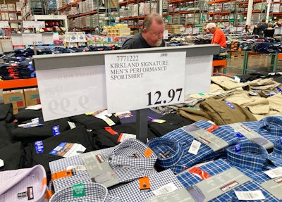 A sign displays the price for shirts as a shopper peruses the offerings at a Costco warehouse on Thursday, June 17, 2021, in Lone Tree, Colo. American consumers faced a third straight monthly surge in princes in June, the latest sign that a rapid reopening of the economy is fueling a pent-up demand for goods and services that in many cases remain in short supply.
