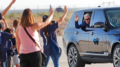Virgin Galactic founder Richard Branson waves to school children while heading to board the rocket plane that will fly him to space from Spaceport America near Truth or Consequences, New Mexico, Sunday, July 11, 2021.