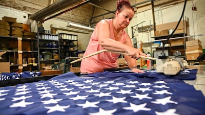 Debbie Wademan, production supervisor, cuts the stars to proper length to make American flags at North American Manufacturing on June 28 in Scranton, Pa.