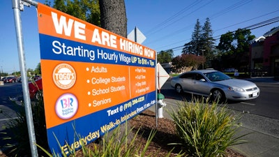 A car passes a hiring banner in Sacramento, Calif., Friday, July 16, 2021. Hiring in California slowed down in June 2021 as employers in the nation's most populous state tried to coax reluctant workers back into their pre pandemic jobs before the nation's expanded unemployment benefits expire in September.