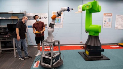 UC students Andrew Barth, left, and Yufeng Sun manipulate robotic arms in UC's Intelligent Robotics and Autonomous Systems Lab.