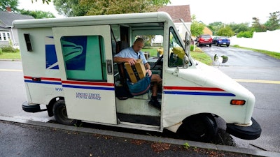 U.S. Postal Service carrier John Graham packs his mail bag after parking a 28-year-old delivery truck, Wednesday, July 14, 2021, in Portland, Maine. The Postal Service’s aging fleet of trucks is soldiering on even as a contract for greener replacement vehicles is being challenged. The primary fleet of vehicles that were delivered starting in 1987 is due to be replaced under a new contract, but the winning bid is being challenged.