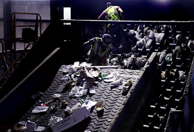 In this Thursday, Sept. 6, 2018, file photo, workers clean consumer plastic shopping bags from the clogged rollers of a machine which separates paper, plastic and metal recyclable material, in a processing building at EL Harvey & Sons, a waste and recycling company, in Westborough, Mass. States around the country are looking to adopt new recycling regimes that require producers of packaging to pay for its inevitable disposal.
