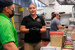 Sarah White, center, area manager of Lost Dog Cafe, trains manager Alex Aleman, left, in a new pasta preparation technique, as they work at the cafe in Fairfax, Va., on Aug. 27.