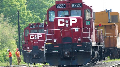 In this May 23, 2012 photo, surveyors work next to Canadian Pacific Rail trains which are parked on the train tracks in Toronto.