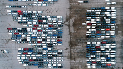 In this March 24 photo, mid-sized pickup trucks and full-size vans are seen in a parking lot outside a General Motors assembly plant where they are produced in Wentzville, Mo.