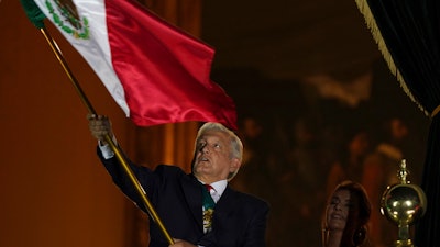 Mexican President Andres Manuel Lopez Obrador waves the national flag after giving the annual independence shout from the balcony of the National Palace, the Zocalo, Mexico City, Sept. 15, 2021.