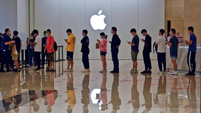 People line up at an Apple Store to buy the latest iPhone 13 handsets in Nanning in south China's Guangxi Zhuang Autonomous Region on Sept. 24, 2021. Global shoppers face possible shortages of smartphones and other goods ahead of Christmas after power cuts to meet government energy use targets forced Chinese factories to shut down and left some households in the dark.