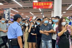 Police stand guard as supporters of Huawei CFO Meng Wanzhou gather at Shenzhen Bao'an International Airport in Shenzhen in southern China's Guangdong Province, Saturday, Sept. 25, 2021. China's government was eagerly anticipating the return of a top executive from global communications giant Huawei Technologies on Saturday following what amounted to a high-stakes prisoner swap with Canada and the U.S.
