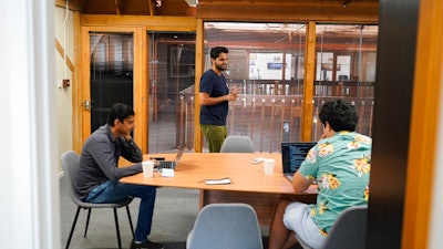 RunX CEO Ankur Dahiya, center, takes part in a meeting with employees Nitin Aggarwal, left, and JD Palomino, right, at a rented office in San Francisco, Friday, Aug. 27, 2021. The eight-worker startup rents the office one day a week so Dahiya can meet with remote working employees who live nearby but other employees are in Canada, Nevada, and Oregon.