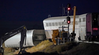 Cars from an Amtrak train that derailed the day before are shown illuminated by floodlights, late Sunday, Sept. 26, 2021, as they rest near a train signal near Joplin, Mont. The westbound Empire Builder was en route to Seattle from Chicago with two locomotives and 10 cars.