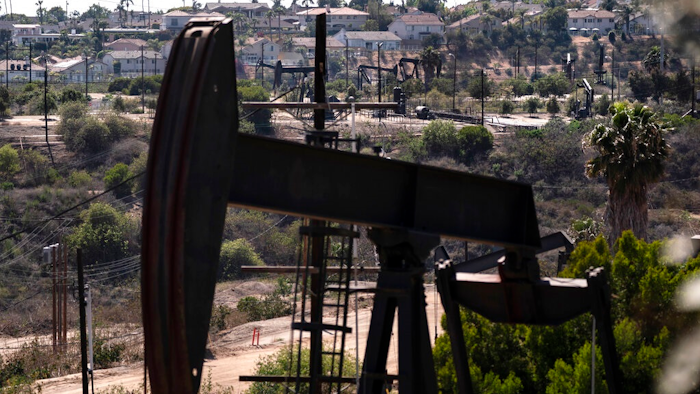 In this May 18, 2021, file photo, homes sit on a hill behind pump jacks operating at the Inglewood Oil Field in Los Angeles. California's oil regulator wants to ban new oil and gas drilling within 3,200 feet of schools, homes and hospitals to protect public health. The draft rule released Thursday, Oct. 21, 2021, would be the nation's largest buffer zone between drilling and community sites if adopted.