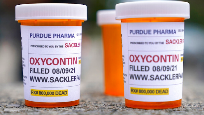 In this Aug. 9, 2021, file photo, fake pill bottles with messages about OxyContin maker Purdue Pharma are displayed during a protest outside the courthouse where the bankruptcy of the company is taking place in White Plains, N.Y. A federal judge on Wednesday, Oct. 13 allowed Purdue Pharma to resume its work carrying out the recent $10 billion settlement plan that allowed the Oxycontin maker to emerge from bankruptcy.