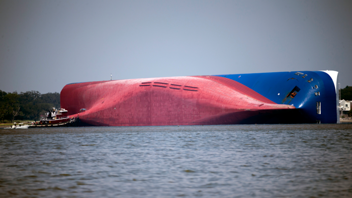 In this Sept. 9, 2019, file photo, a Moran tugboat nears the stern of the capsizing cargo ship Golden Ray as rescuers can be seen near the bottom of the ship near the tug boat, off St. Simons Island, Ga. The final giant chunk of an overturned cargo ship has been removed from waters along the coast of Georgia.