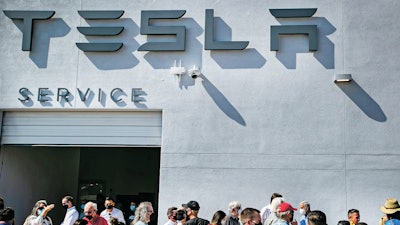 Tesla owners, Tesla employees and local political leaders gather at the service bay doors during an event on Sept. 9, 2021, to celebrate a partnership between Tesla and the Nambé Pueblo after the electric car company repurposed a defunct casino into a sales, service and delivery center near Santa Fe, N.M. Tesla has opened a store on tribal land in New Mexico, sidestepping car dealership laws that prohibit car companies from selling directly to customers.