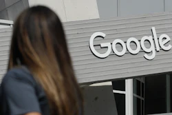 In this Sept. 24, 2019, file photo, a woman walks below a Google sign on the campus in Mountain View, Calif. Google on Thursday, Oct. 7, 2021, will no longer allow digital ads promoting false climate change claims to appear next to the content of other publishers, hoping to deny money to those making such claims and to stop the spread of misinformation on its platform.