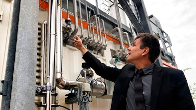 Dietrich Brockhagen, Executive Director of Atmosfair, points on pipes of the system that brings hydrogen and carbon into the facility that mix them and produce e-fuel at the 'Atmosfair' synthetic kerosene plant in Werlte, Germany, Monday, Oct. 4, 2021. German officials are unveiling a facility in Werlte, near Germany's northwestern border with the Netherlands, what they say will be the world's first commercial plant for making synthetic kerosene as part of an effort to reduce the climate impact of flying.