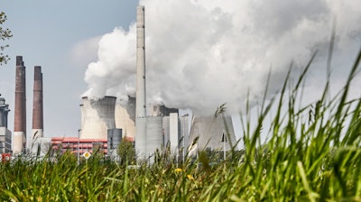 In this Thursday, April 29, 2021 file photo, a coal-fired RWE power plant steams on a sunny day in Neurath, Germany. The International Energy Agency is urging governments to make stronger commitments to cut greenhouse gas emissions at an upcoming U.N. climate summit.