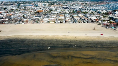 In this Wednesday, Oct.6, 2021 aerial image taken with a drone, workers in protective suits clean the contaminated beach after an oil spill in Newport Beach, Calif. California's uneasy relationship with the oil industry is being tested again by the latest spill to foul beaches and kill birds and fish off Orange County.