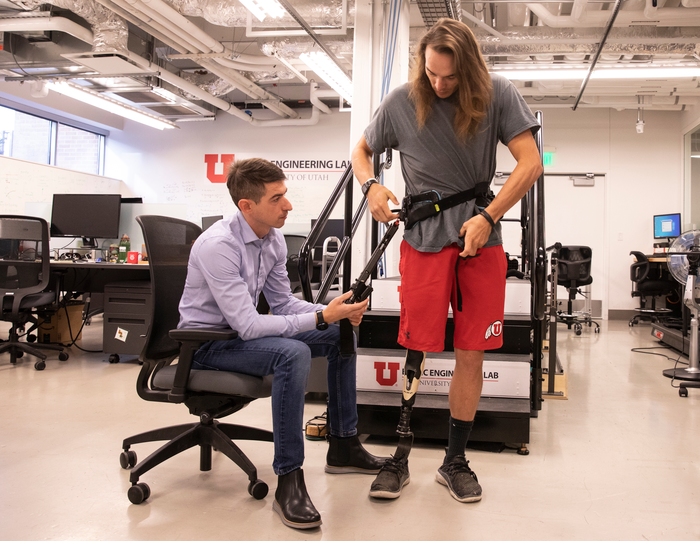 University of Utah mechanical engineering assistant professor Tommaso Lenzi, left, helps Alec McMorris put on an experimental exoskeleton that Lenzi has developed for lower-limb amputees.