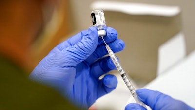 In this Oct. 5, 2021, file photo a healthcare worker fills a syringe with the Pfizer COVID-19 vaccine at Jackson Memorial Hospital in Miami. President Joe Biden’s most aggressive move yet to combat the COVID-19 pandemic is almost ready to see the light of day. The government is close to publishing the details of a new vaccination-or-testing rule covering more than 80 million Americans at companies with 100 or more workers.