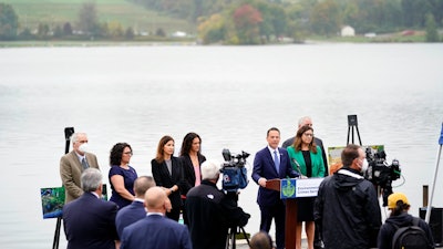 Pennsylvania Attorney General Josh Shapiro, at podium, speaks during a news conference at Marsh Creek State Park in Downingtown, Pa., Tuesday, Oct. 5, 2021. Shapiro filed criminal charges Tuesday against the developer of a problem-plagued pipeline that takes natural gas liquids from the Marcellus Shale gas field to an export terminal near Philadelphia.