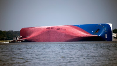 In this Sept. 9, 2019, file photo, a Moran tugboat nears the stern of the capsizing cargo ship Golden Ray as rescuers can be seen near the bottom of the ship near the tug boat, off St. Simons Island, Ga. The final giant chunk of an overturned cargo ship has been removed from waters along the coast of Georgia.